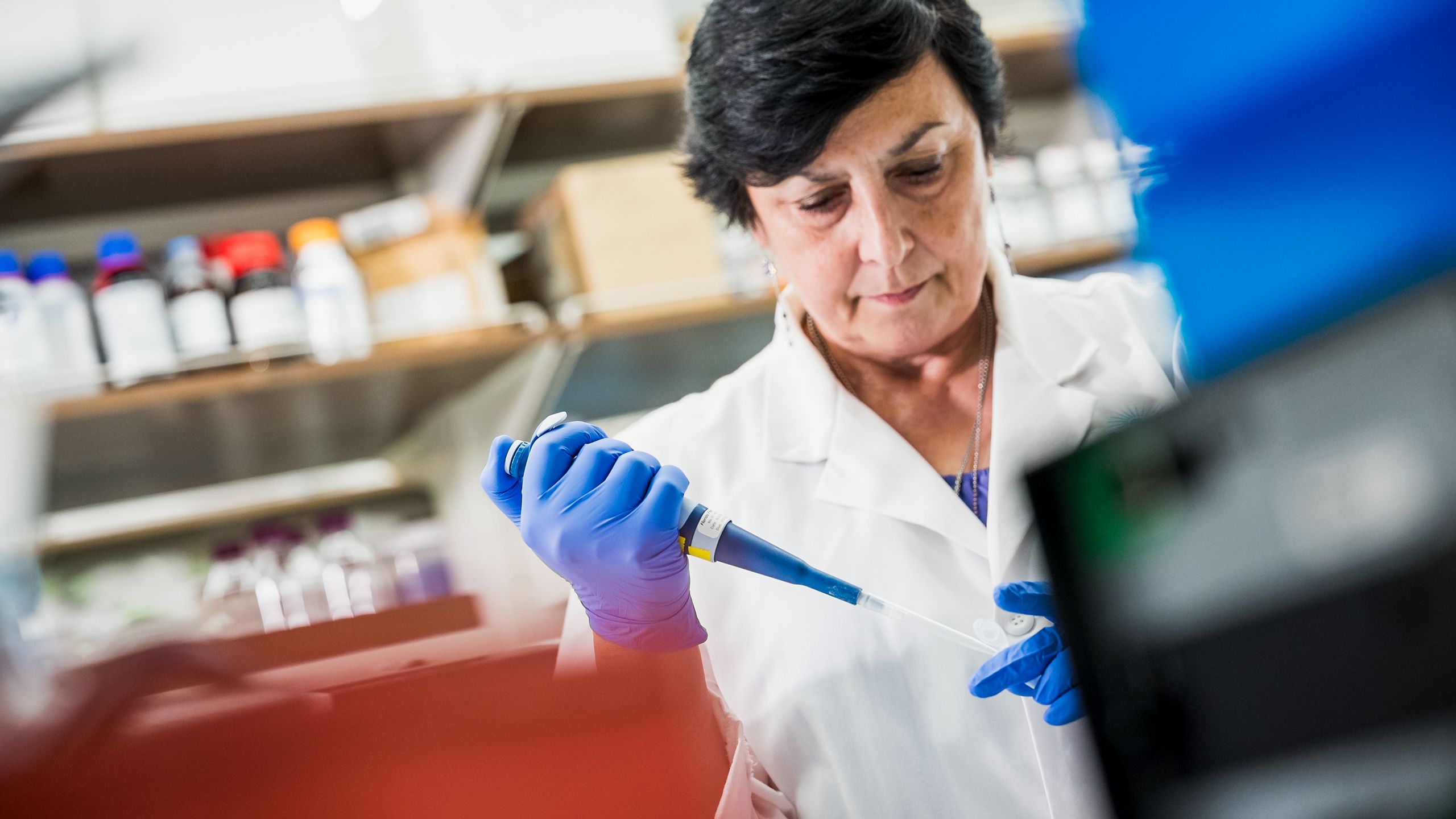 woman in lab using a pipette to fill a test tube