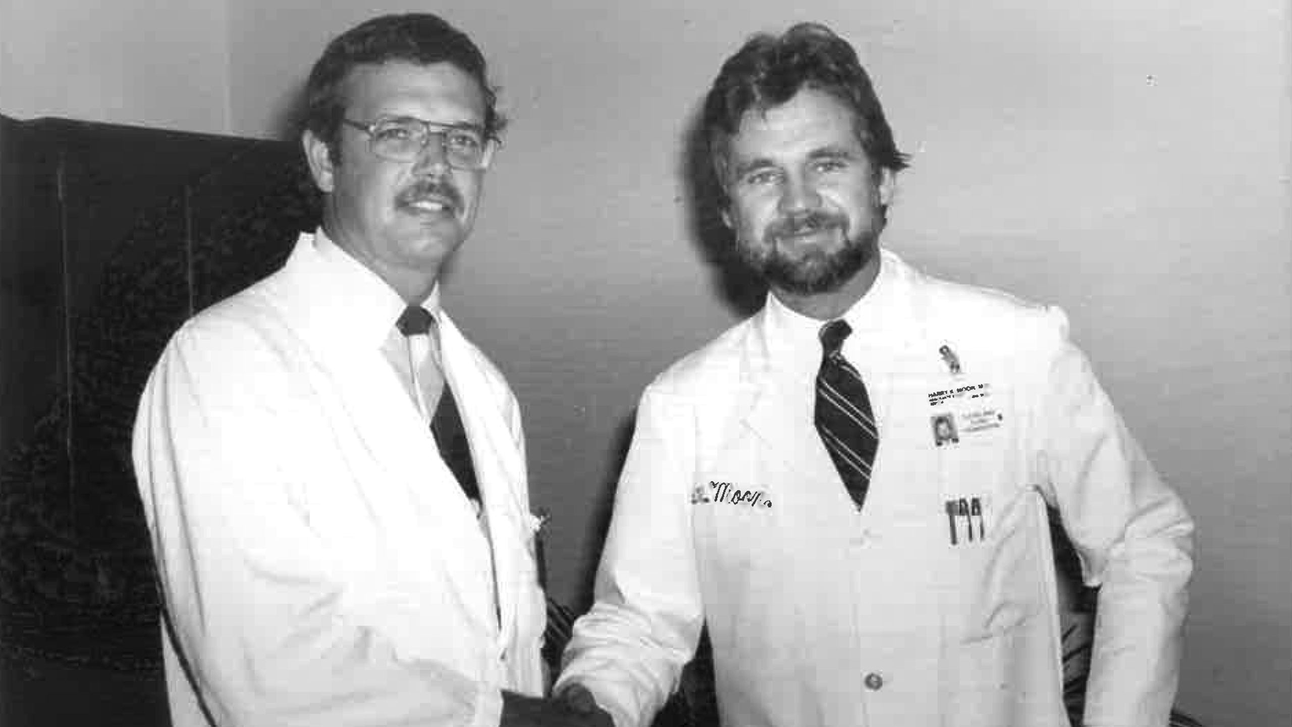 Dr. Moon as a young doctor shaking hands with a a fellow doctor.
